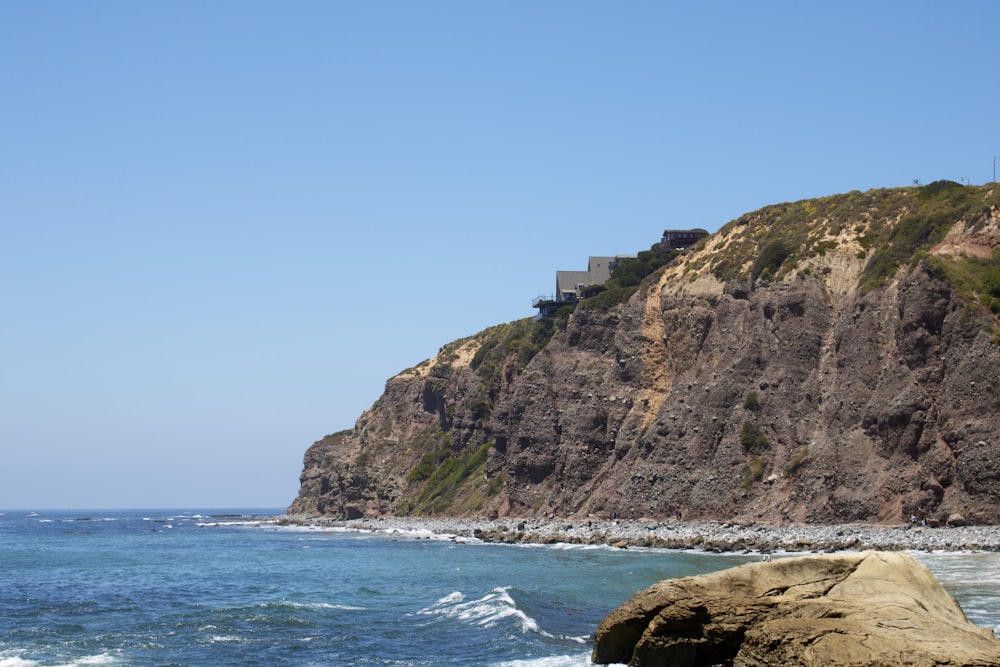white concrete building on cliff by the sea under blue sky during daytime