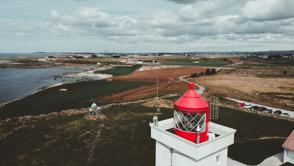 white and red concrete tower on green grass field under cloudy sky during daytime