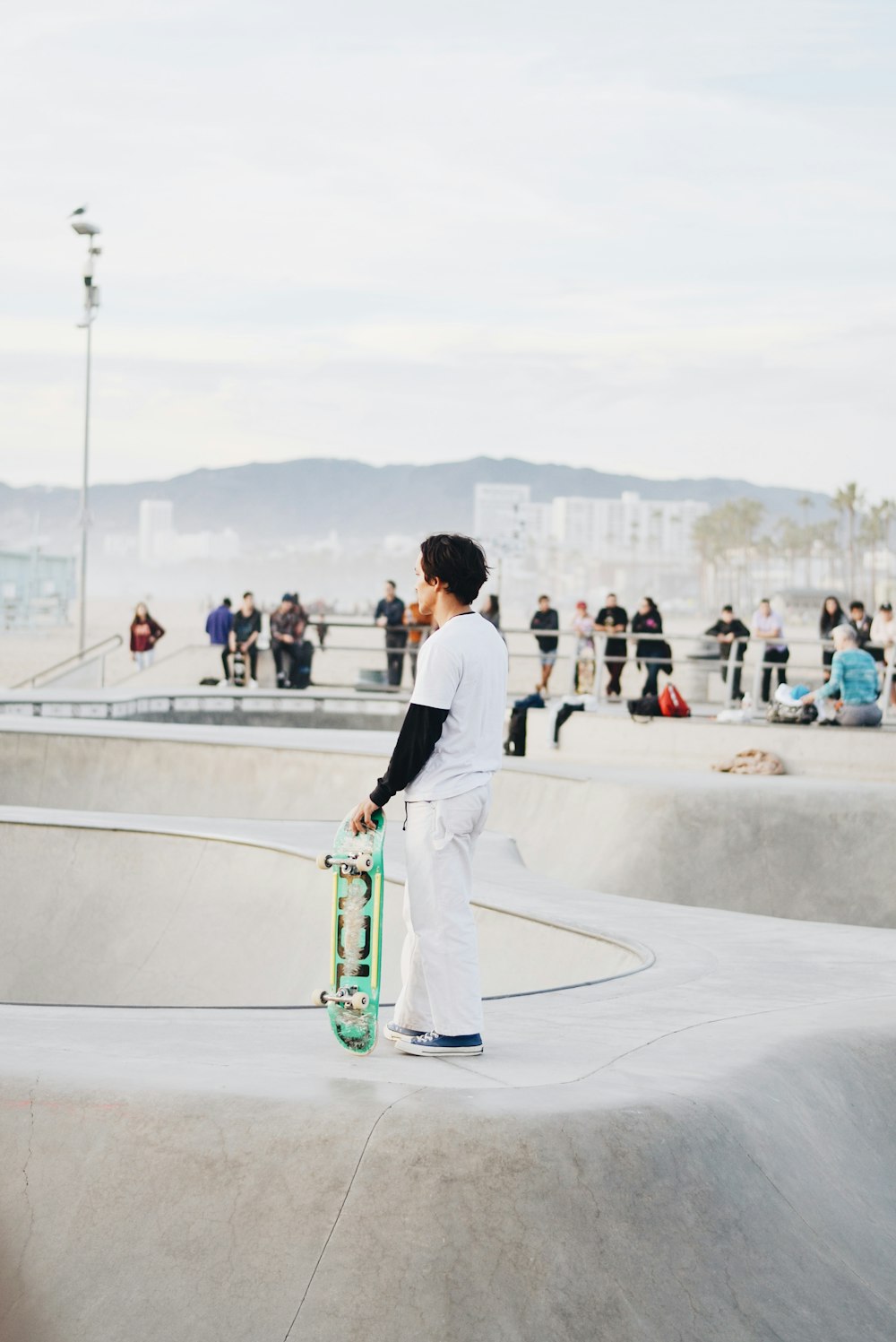 man in white dress shirt and green pants sitting on green skateboard during daytime