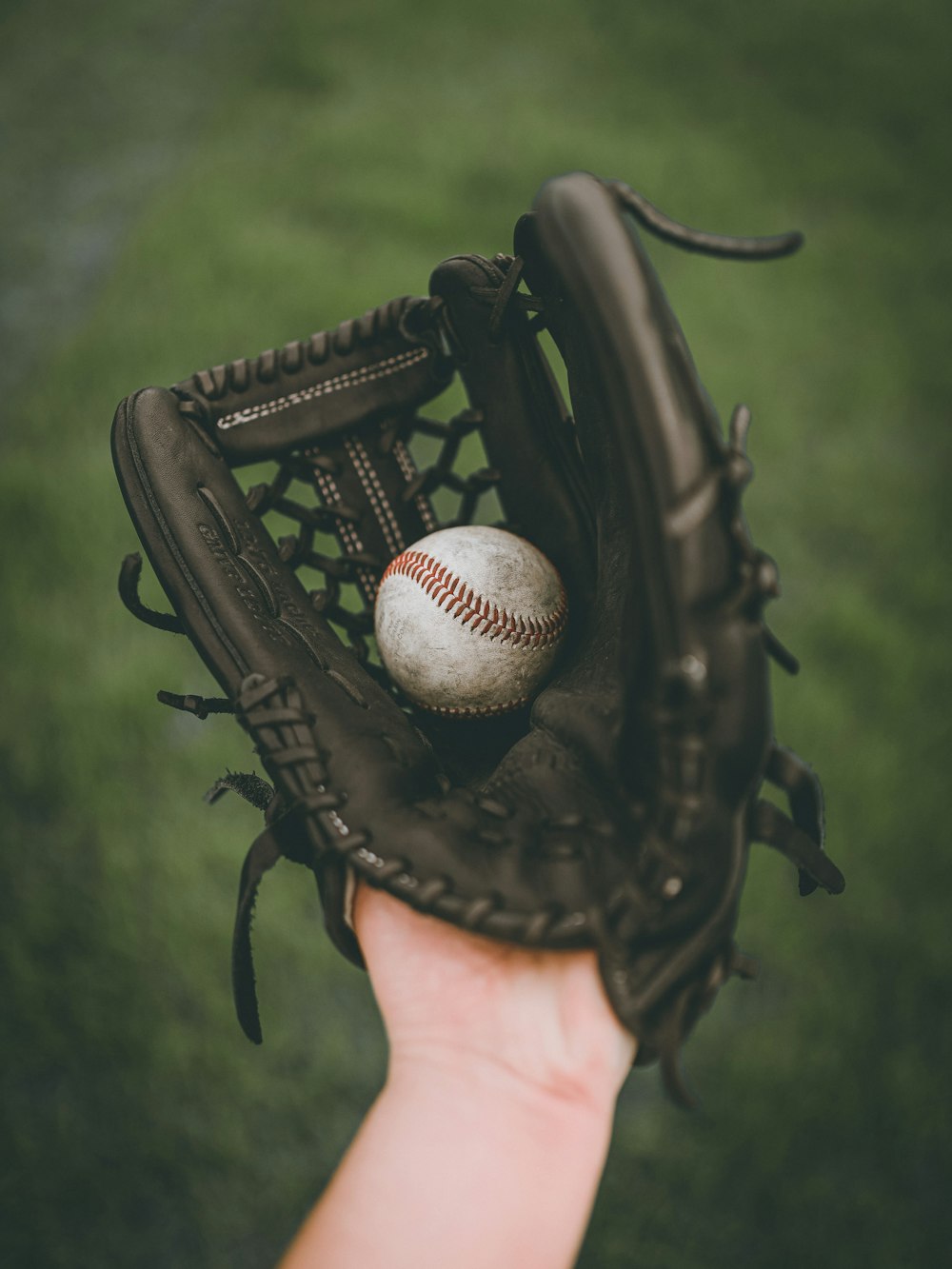 Personne tenant une balle de baseball dans une mitaine de baseball en cuir noir