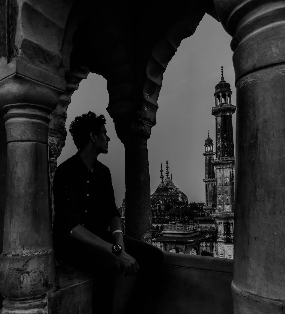 grayscale photo of man in black shirt sitting on bench