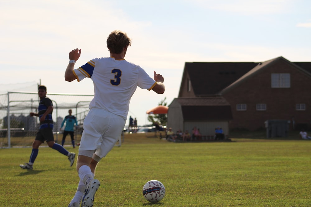 boy in white soccer jersey kicking soccer ball