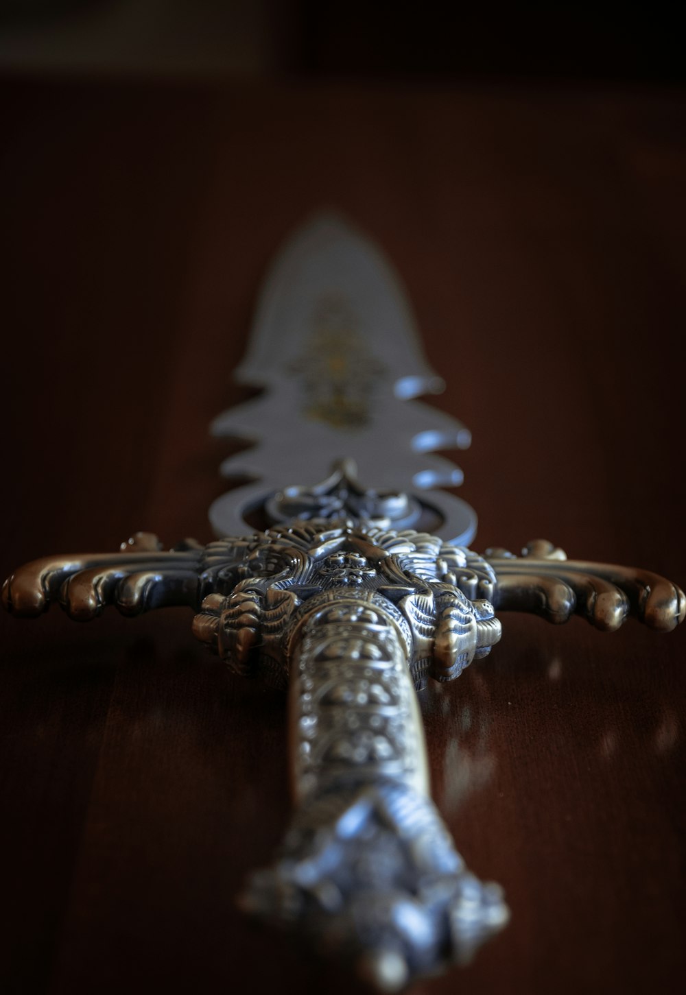 espada de plata sobre mesa de madera marrón