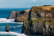 person standing on cliff near sea during daytime