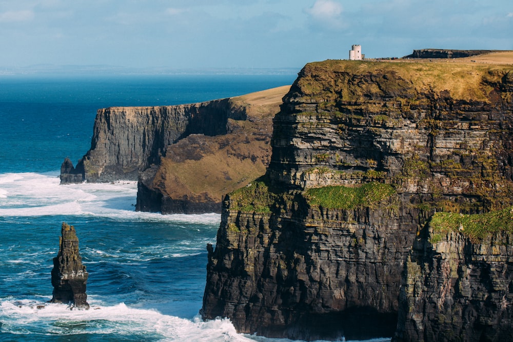 person standing on cliff near sea during daytime