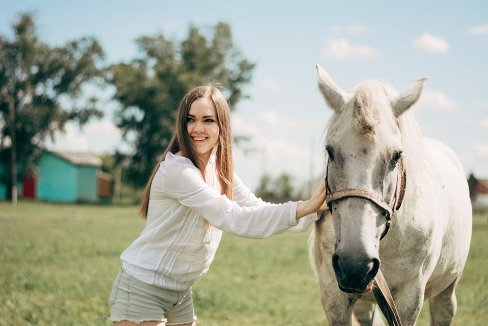 woman in white long sleeve shirt riding white horse during daytime