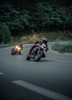 a couple of people riding motorcycles down a curvy road