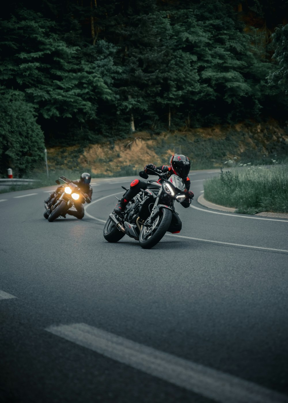 a couple of people riding motorcycles down a curvy road