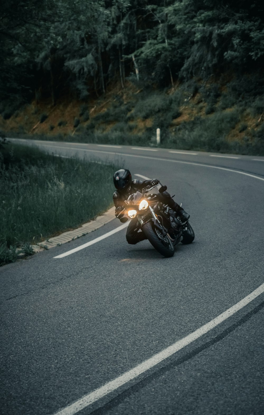 Ein Mann fährt mit dem Motorrad eine kurvige Straße hinunter