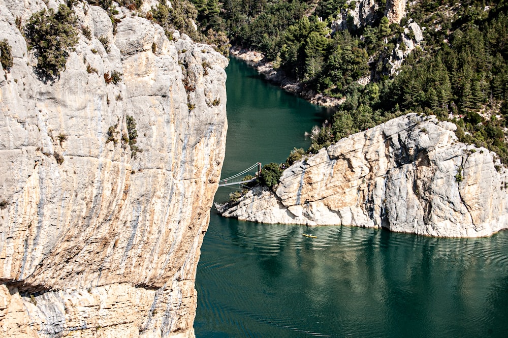 brown rocky mountain beside green river during daytime