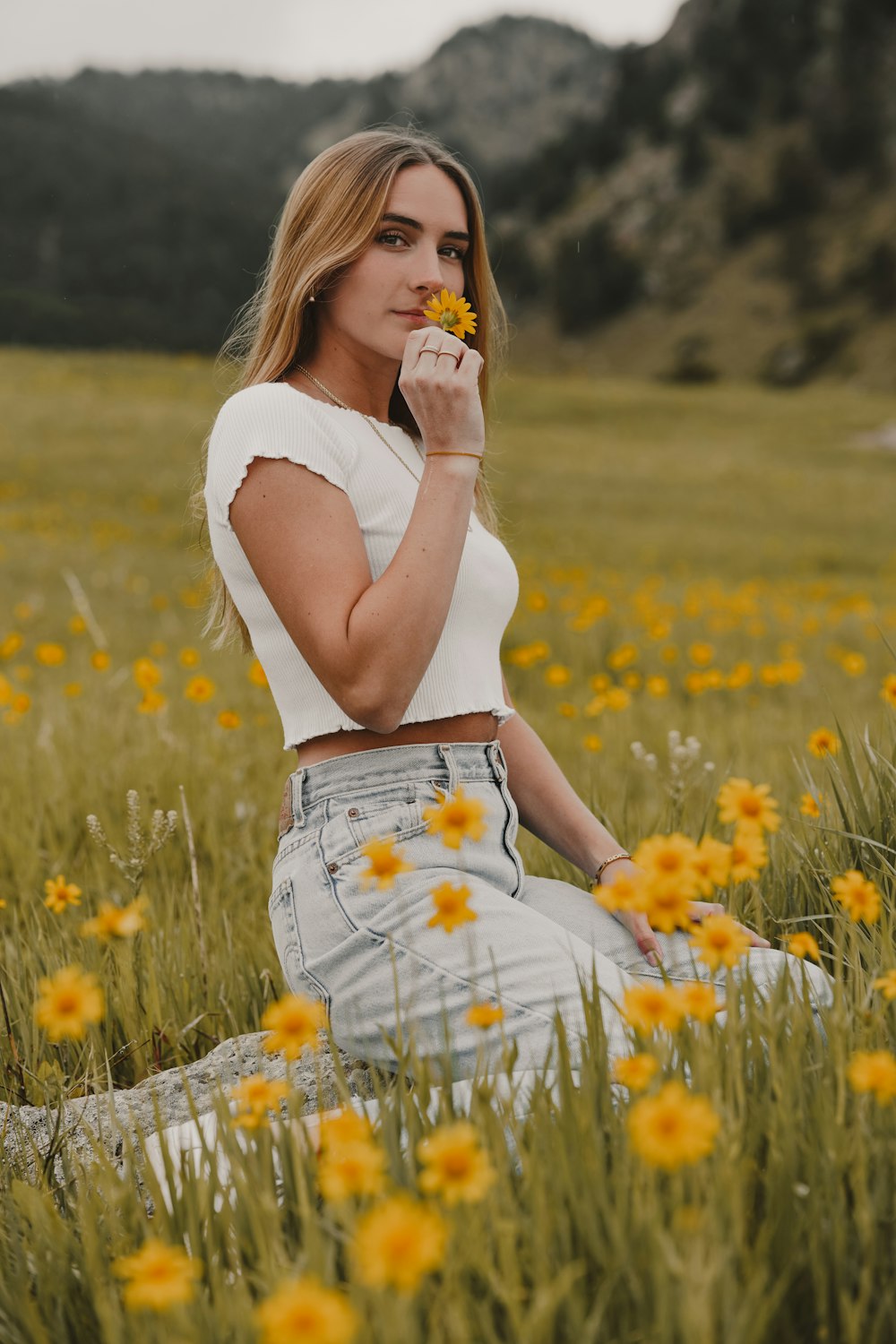 woman in white tank top and white skirt sitting on green grass field during daytime