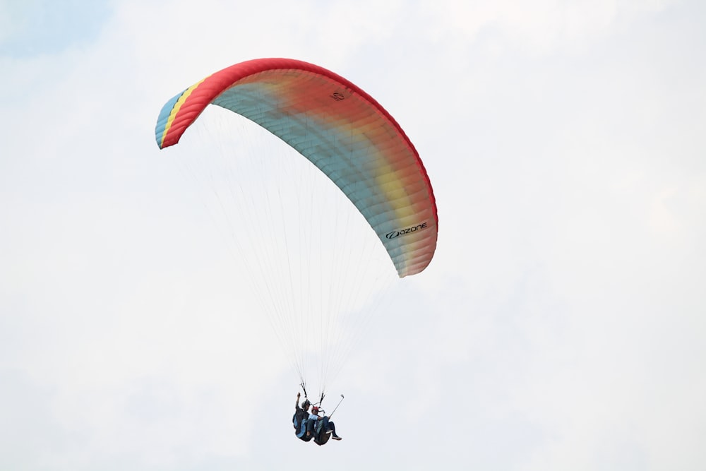 person in black jacket riding orange and yellow parachute