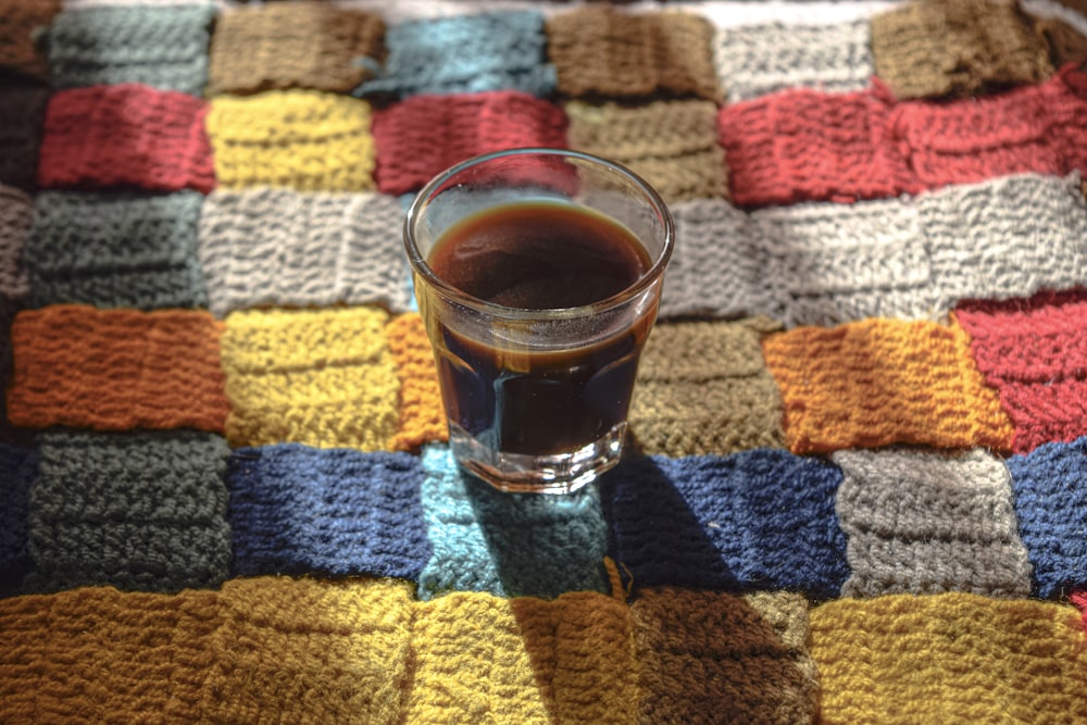 clear drinking glass on brown and white knit textile