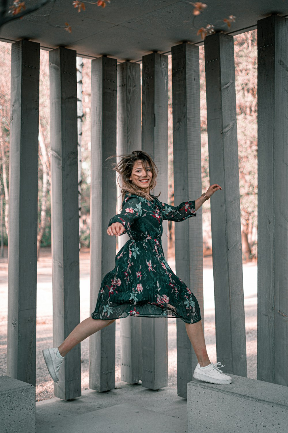 woman in blue and red floral dress standing beside white wooden fence