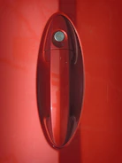 Close-up of a locksmith picking a car door lock on a sleek vehicle.