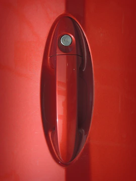 Close-up of a locksmith picking a car door lock on a sleek vehicle.