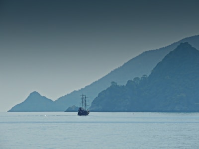 A calm sea at dawn with a silhouette of a rescue ship on the horizon.
