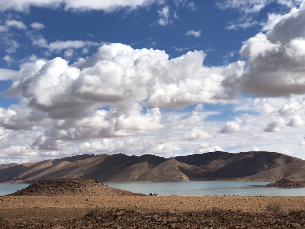 brown field under white clouds and blue sky during daytime