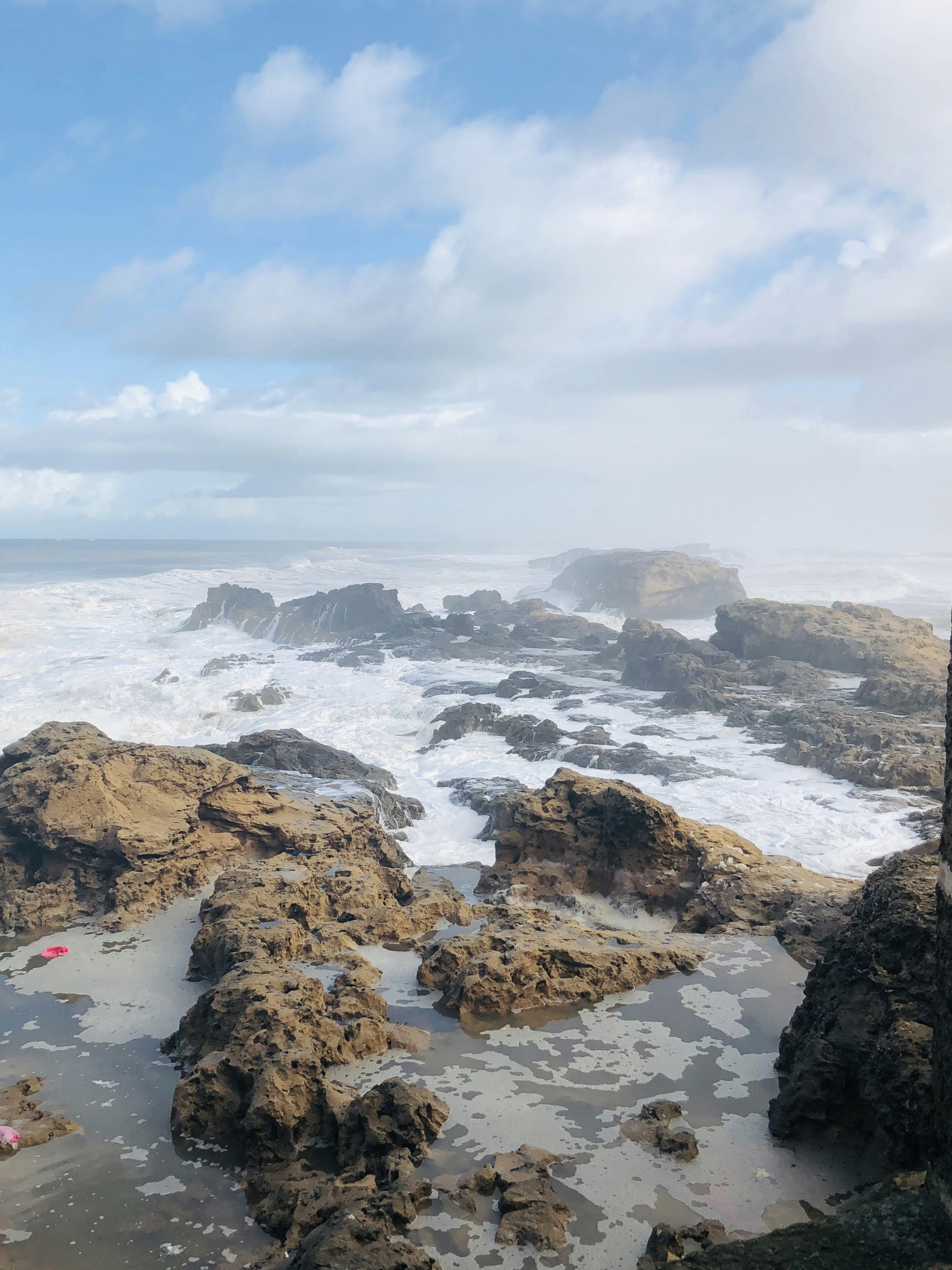 brown rock formation on sea under white clouds during daytime