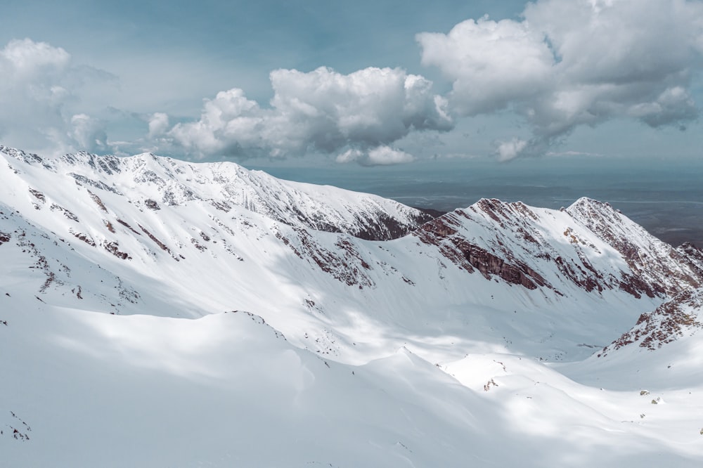 snow covered mountain under white clouds during daytime