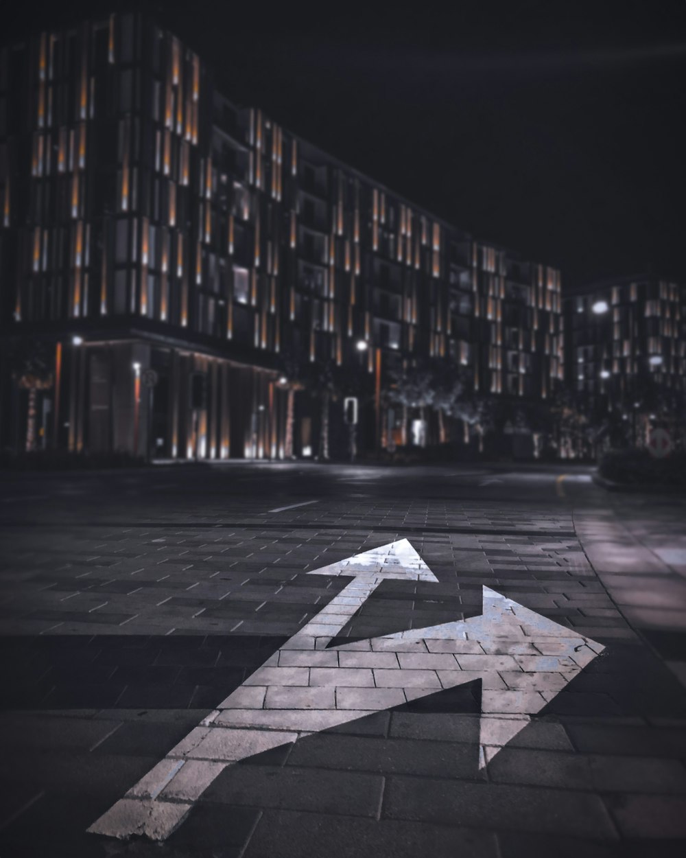 Grau-weiße Sterndruck-Betonstraße zwischen Hochhäusern während der Nacht