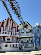 white and red concrete building beside palm tree under blue sky during daytime