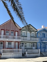 white and red concrete building beside palm tree under blue sky during daytime