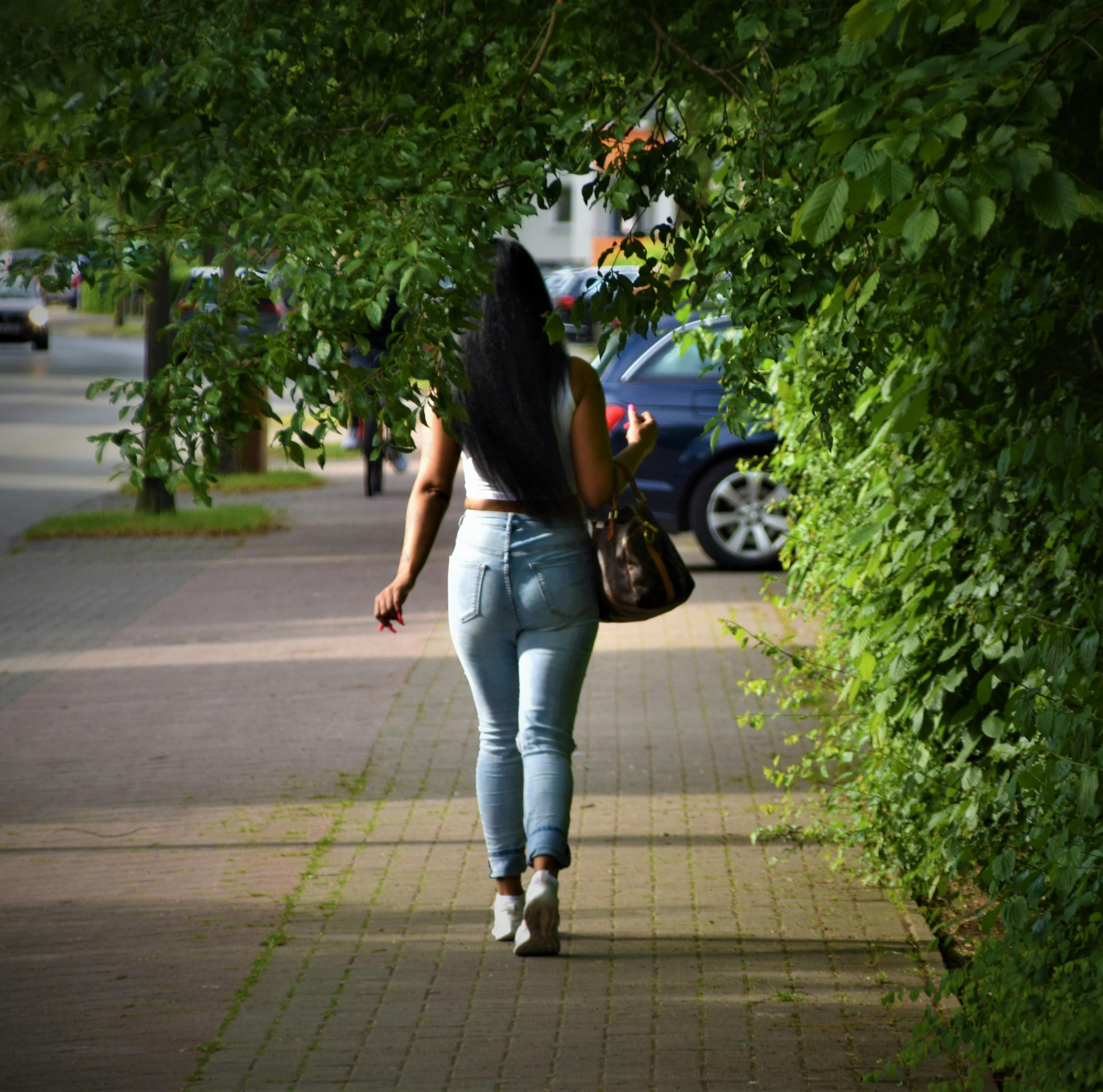 woman in blue denim jeans standing on sidewalk during daytime
