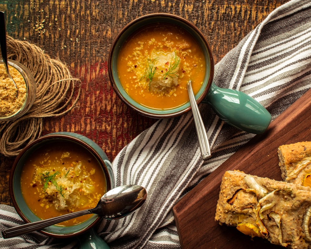 soup in brown ceramic bowl beside silver spoon and fork