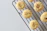 Round cookies with a crumbly texture are placed on a black metal cooling rack. Sprinkles of nuts or seeds are visible on the tops of the cookies, and the background is a plain, light gray surface.