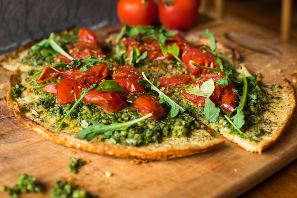 pizza with tomato and green leaves on brown wooden table