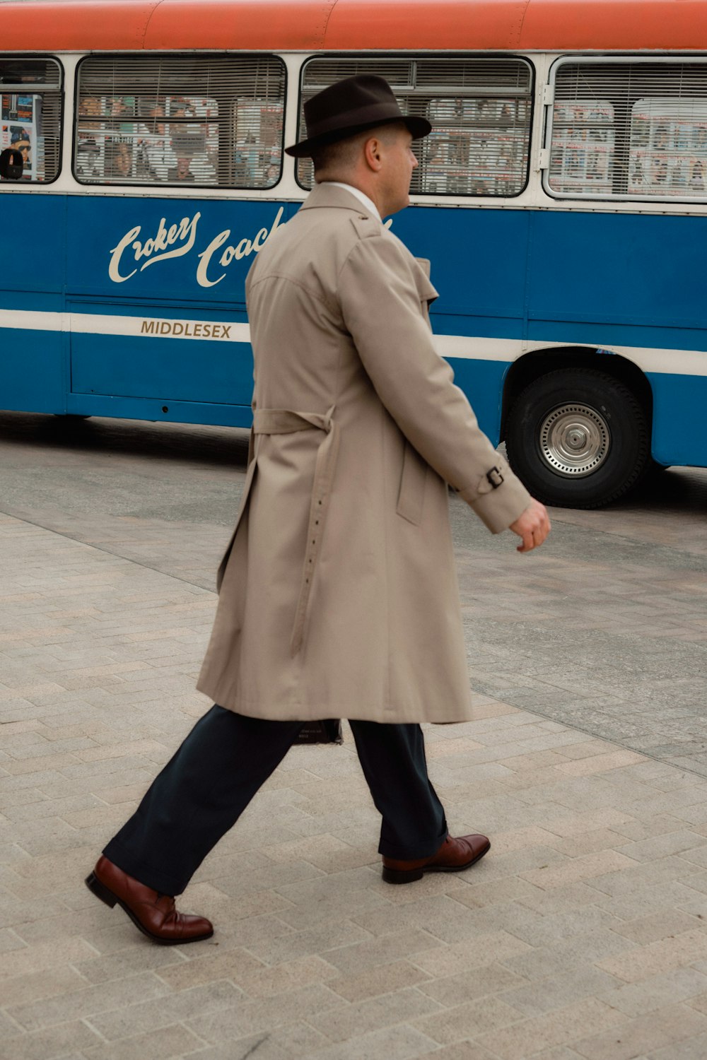woman in gray coat walking on sidewalk during daytime