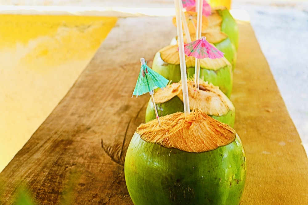 green coconut with white straw on brown wooden table