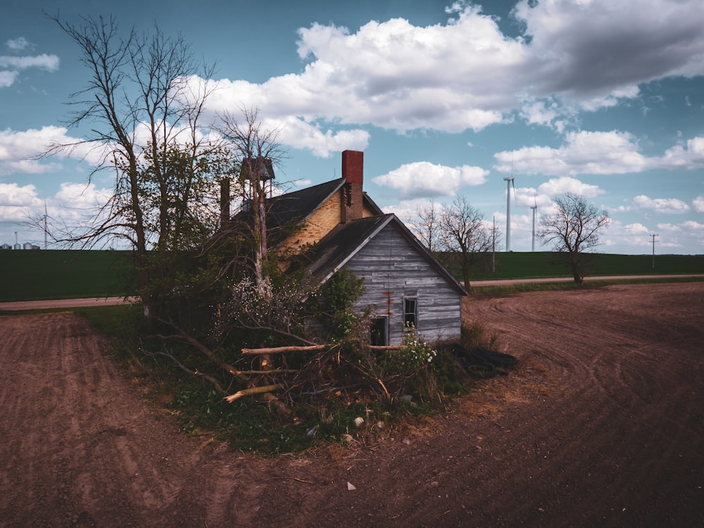 brown wooden house near bare tree under white clouds during daytime