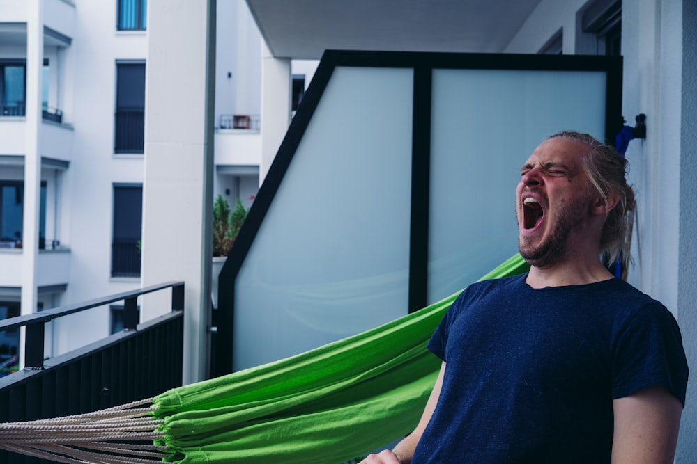 man in blue crew neck shirt standing beside green hammock