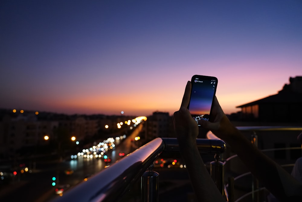 person taking photo of city during night time