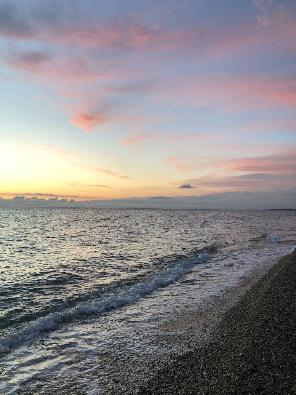 ocean waves crashing on shore during sunset