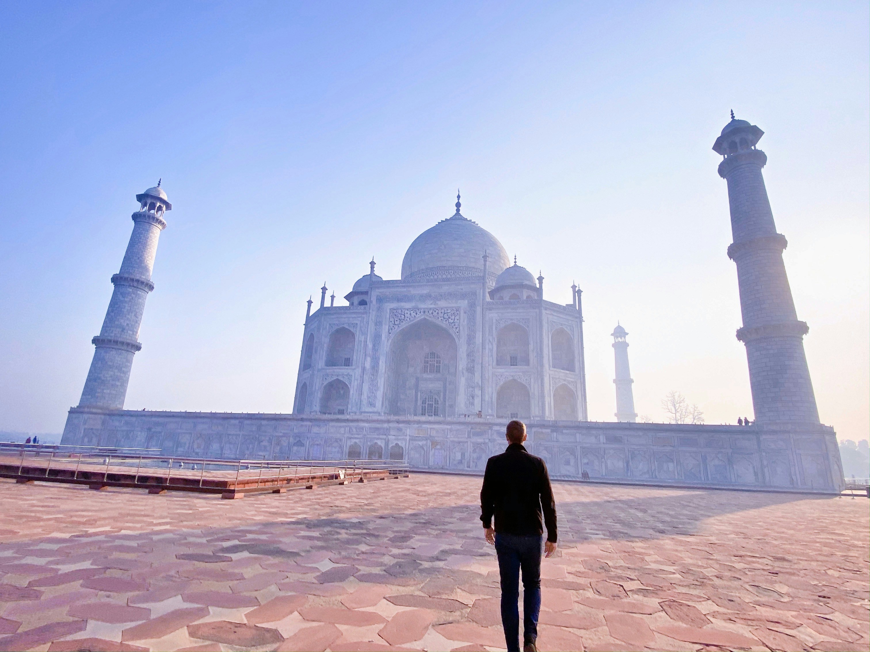 man in black jacket standing near mosque during daytime, 