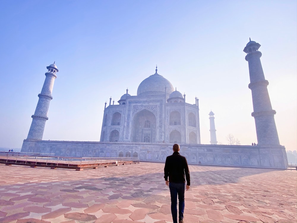 man in black jacket standing near mosque during daytime