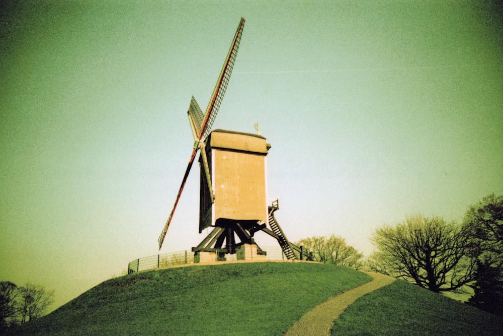 Molino de viento marrón en campo de hierba verde bajo cielo gris