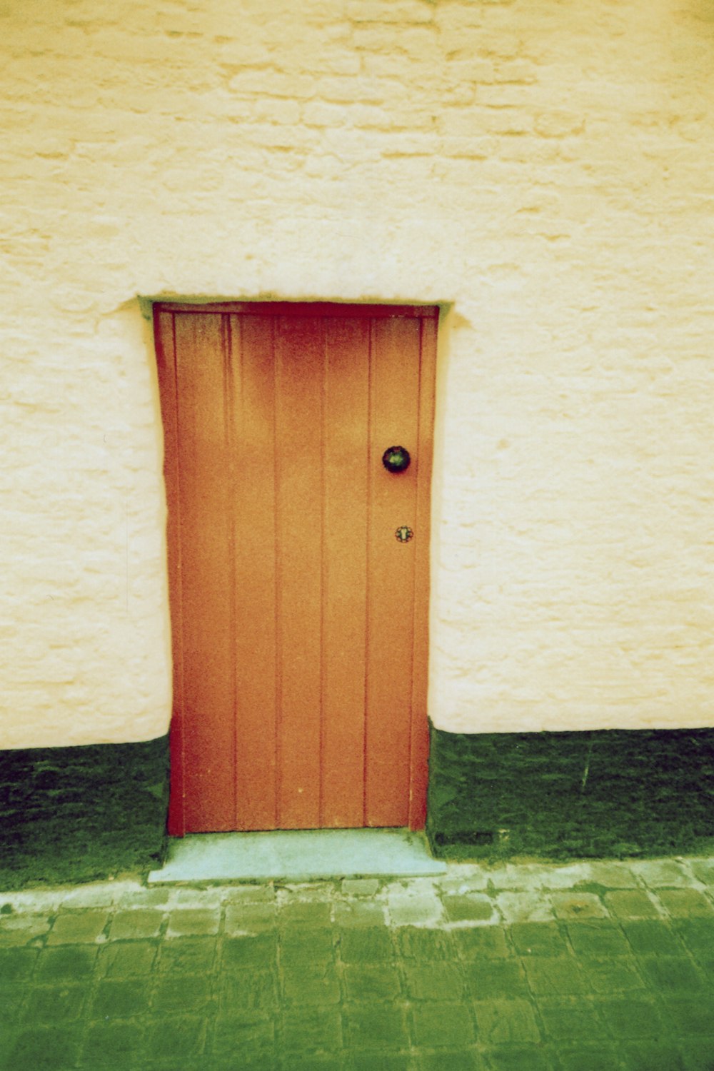 puerta de madera roja sobre pared de hormigón blanco