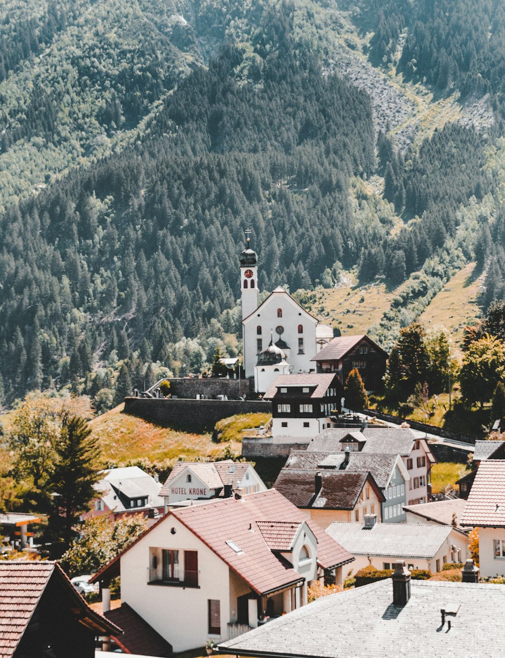 white and brown concrete house near green trees and mountains during daytime