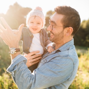 man in blue denim jacket carrying girl in white sweater during daytime