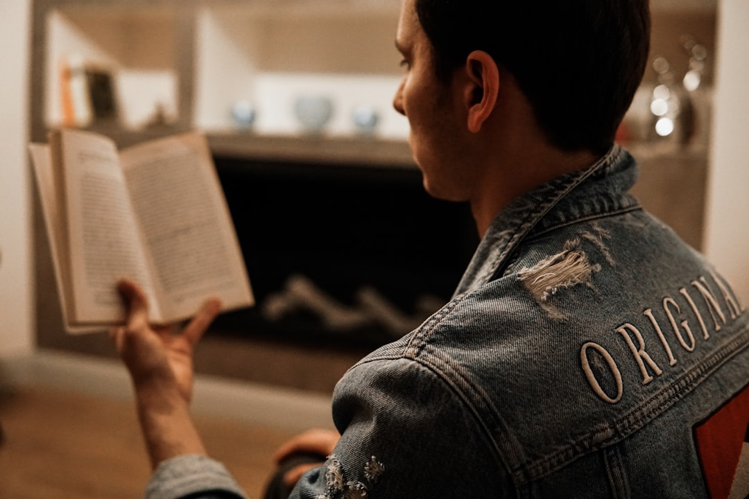 man in blue denim jacket reading book