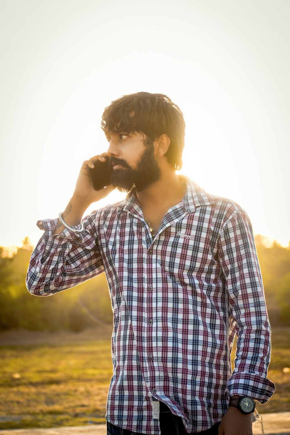 man in blue and white plaid dress shirt standing during daytime