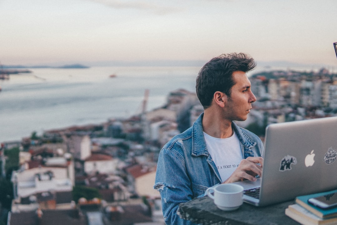 man in blue denim jacket using macbook air