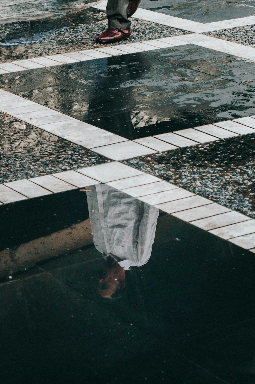 person in white pants standing on white and black concrete floor