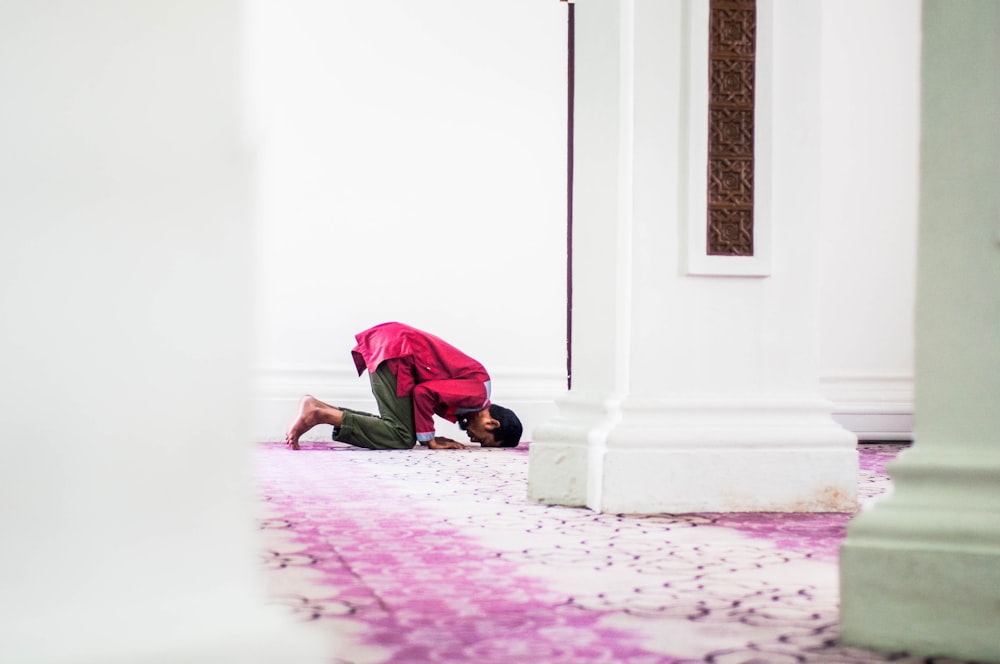 man in green long sleeve shirt and black pants sitting on floor