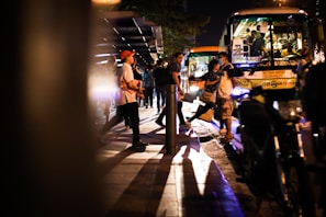 A bus driver assisting passengers with luggage at a busy bus stop.
