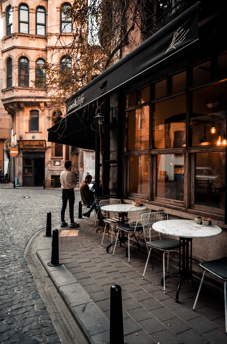 Pavement tables outside a corner café on a city street.